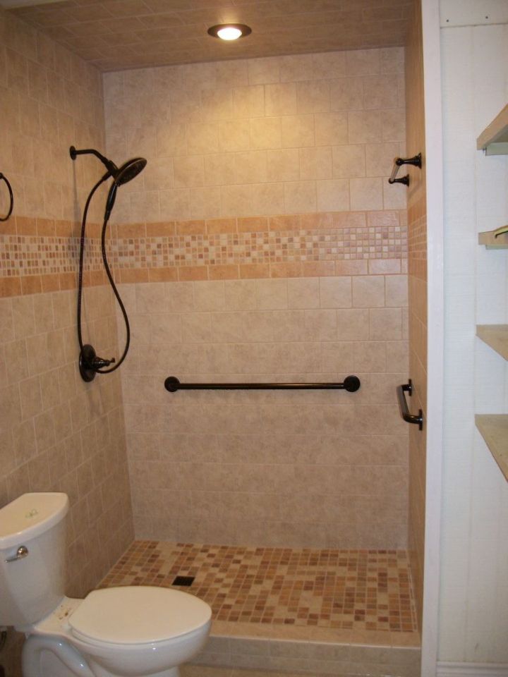 noce tile shower with accent band in gold and mosaic colors